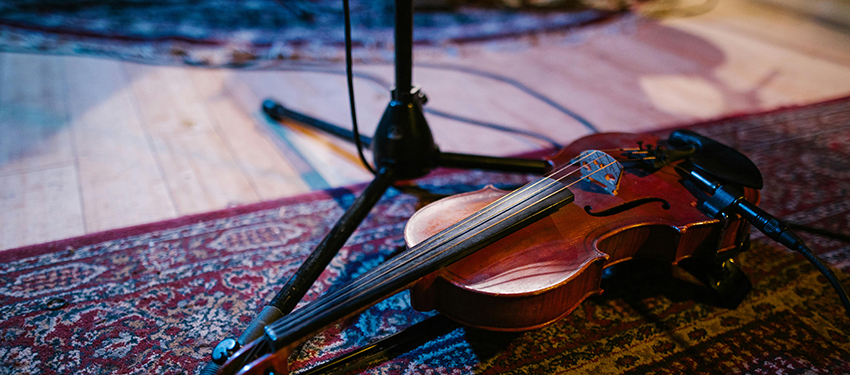 A string instrument sitting on the floor next to a sheet music stand